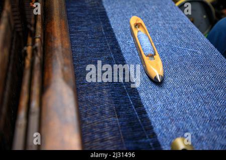 La navetta di Weaver si trova su tessuti tweed, Isle of Harris, Outer Hebrides, Scotland UK Foto Stock