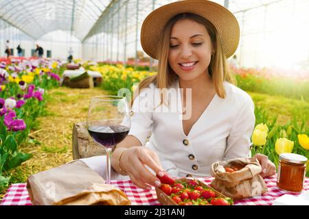 Picnic tra i tulipani in primavera. Bella donna seduta tra fiori godendo di cibi biologici locali in Toscana, Italia. Foto Stock