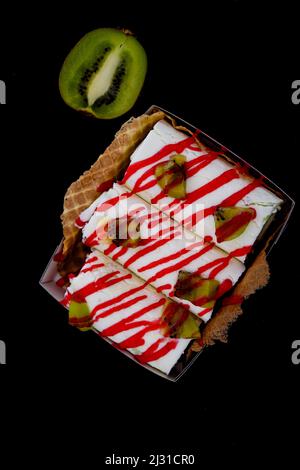 Gelato arrotolato con fragola in tazza a cono su sfondo nero scuro. Foto Stock
