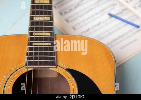 Scena di registrazione musicale con chitarra, fogli musicali e matita su tavolo di legno, primo piano Foto Stock