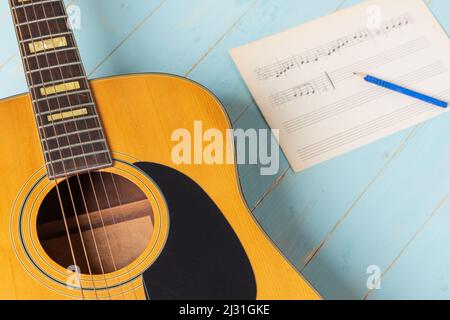 Scena di registrazione musicale con chitarra, spartiti musicali e matita su tavolo di legno, primo piano Foto Stock