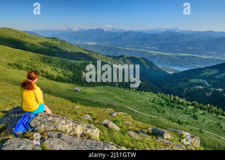 Donna mentre escursioni si siede sulla roccia e guarda verso la valle, Kampnock, Nockberge, Nockberge-Trail, Unesco Nockberge Biosphere Park, Gurktal Alpi, Carinzia, Austria Foto Stock