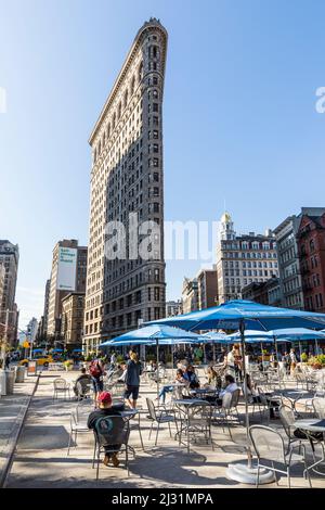 NEW YORK, USA - Oct 5, 2017: Le persone godono di sedersi su sedie pubbliche broadwayon con wlan gratuito e guardando alla spettacolare facciata del palazzo Flatiron Foto Stock