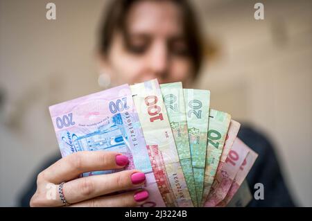 Immagine del primo piano di Bundle di 10, 20, 100 e 200 Bills tenuto in mano da un silhouette di una donna che li guarda Foto Stock