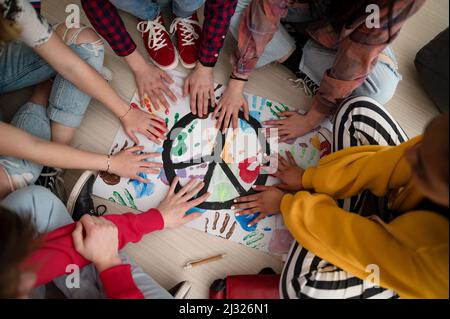 Vista dall'alto degli studenti che fanno un poster di segno di pace a scuola. Foto Stock