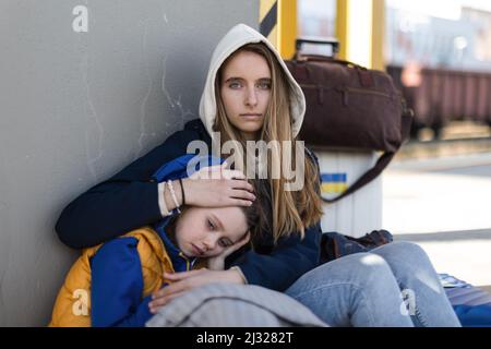 Depressi immigrati ucraini seduti e in attesa alla stazione ferroviaria. Foto Stock