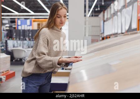 Giovane donna che sceglie la copertura del pavimento, laminato in ferramenta store Foto Stock