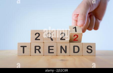 2022 concetto di tendenza. Mano flip cubo di legno cambiare anno 2021 a 2022. Bellissimo sfondo bianco, spazio di copia. Utilizzato per banner in concetto di tendenza in New YE Foto Stock