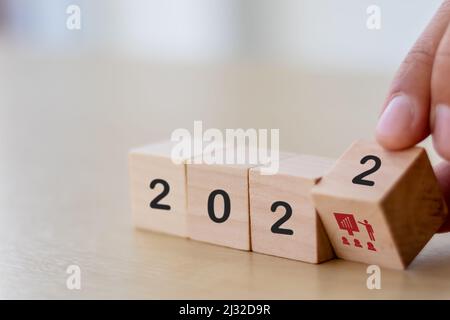 Concetto di formazione e condivisione delle conoscenze. Piano di formazione della forza lavoro e del team nel 2022. L'uomo d'affari capovolge i cubi di legno con 2022 e simboli di addestramento sopra Foto Stock