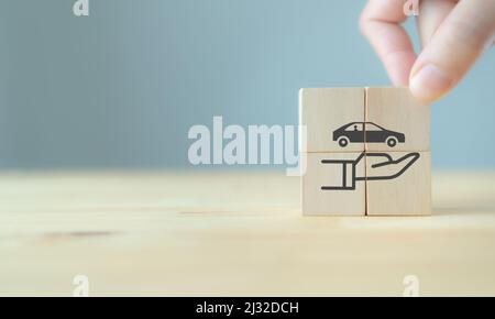 Assicurazione auto (automobile) e concetti di esonero da collisione danni. La mano tiene i cubetti di legno con il simbolo di protezione di cura su sfondo grigio e copia Foto Stock