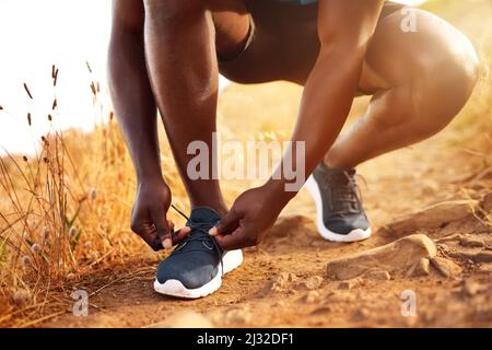 Allenati per il fitness. Un'immagine ritagliata di un uomo inidentificabile che lega le sue scarpe prima di una corsa all'aperto. Foto Stock