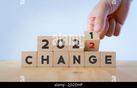 Cambiamento di concetto nel nuovo anno 2022 . Decisione che cambia la vita e nuove opportunità. La mano capovolge i cubi di legno da 2021 a 2022 con il testo 'CHANGE' su beautiful Foto Stock