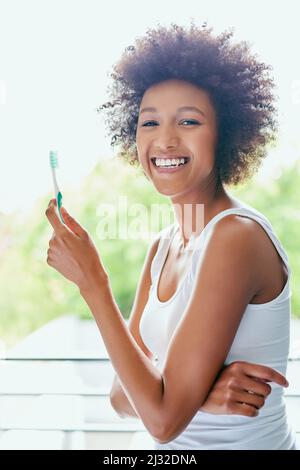 Respiro fresco, ora pronto per la giornata. Scatto corto di una giovane donna attraente spazzolando i denti nel bagno di casa. Foto Stock
