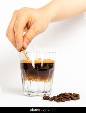 Una mano prepara una bevanda a base di caffè espresso tonico su sfondo bianco Foto Stock