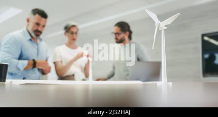 Professionisti del design creativo che lavorano con 3D modelli di turbine eoliche in un ufficio moderno. Gruppo di uomini d'affari innovativi che si sfidano mentre lavorano o Foto Stock