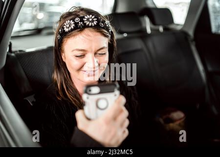 Un taxi o un passeggero Uber che parla al telefono sul sedile posteriore dell'auto Foto Stock