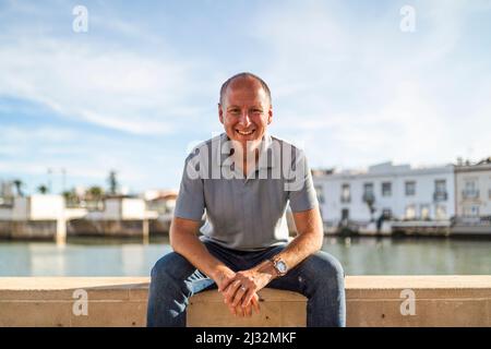 Ritratto di uomo sorridente rilassante sulla riva del fiume in turistico e storico Tavira, Algarve, Portogallo Foto Stock