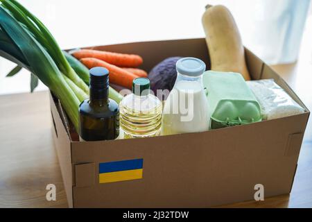 Box alimentare per i rifugiati di guerra ucraini - concetto di aiuto umanitario - Focus sulla bandiera ucraina Foto Stock