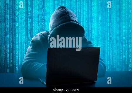 Hacker che utilizza un computer portatile per organizzare un attacco di violazione massiccia dei dati sui server aziendali. Persona anonima nel cofano seduto di fronte al computer Foto Stock