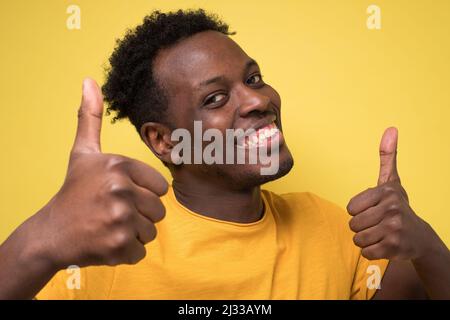 Ritratto di felice afroamericano bel uomo ridendo e mostrando pollice su gesto Foto Stock