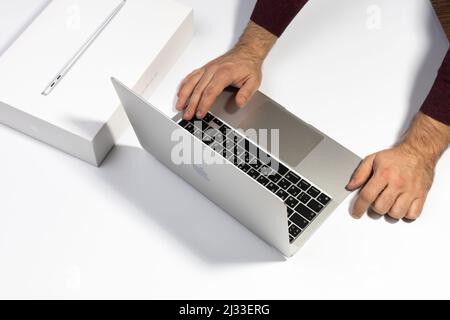 Saratov, Russia - 26 febbraio 2022: Lavora su MacBook Air da 13 pollici con processore M1. Disimballaggio del nuovo primo piano del notebook Apple, sfondo bianco. Pubblicità Foto Stock