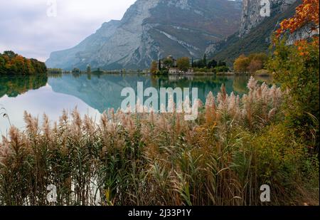 Lago Toblino con il castello in forma autunnale. È un piccolo lago alpino in provincia di Trento (Trentino-Alto Adige) ed è stato dichiarato Biotopo per le sue qualità naturalistiche. Posizione utilizzata per la produzione di pellicole. Italia Foto Stock