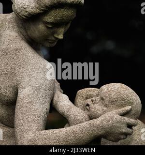 L'amore di una madre. Una donna sostiene delicatamente la testa del bambino mentre si prepara ad allattarlo, in questo dettaglio quadrato di "abbondanza" dello scultore britannico Francis Derwent Wood (1871-1926). La statua, insieme ad altre due, costituisce il fulcro scultoreo del Rose Garden di Hampton Court, lo storico palazzo reale fondato nel XVI secolo accanto al Tamigi nel borgo londinese di Richmond-upon-Thames, Inghilterra. Foto Stock