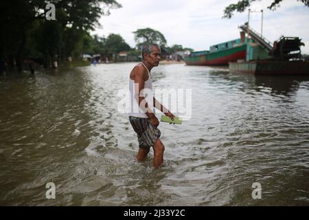 Un uomo attraversa le acque allagate di Sunamganj, nel nord-est del Bangladesh, il 15 luglio 2020. Ogni anno milioni di persone colpite da alluvioni a causa di forti piogge e di fiumi in eccesso nelle parti nord-orientali e nord-occidentali del Bangladesh. Molte persone sono morte, sfollate, hanno perso le loro colture, le loro case, la sofferenza per gli alimenti e l'acqua potabile pura durante l'alluvione del monsone. Foto Stock