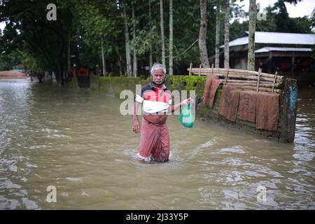 Un uomo attraversa le acque allagate di Sunamganj, nel nord-est del Bangladesh, il 15 luglio 2020. Ogni anno milioni di persone colpite da alluvioni a causa di forti piogge e di fiumi in eccesso nelle parti nord-orientali e nord-occidentali del Bangladesh. Molte persone sono morte, sfollate, hanno perso le loro colture, le loro case, la sofferenza per gli alimenti e l'acqua potabile pura durante l'alluvione del monsone. Foto Stock