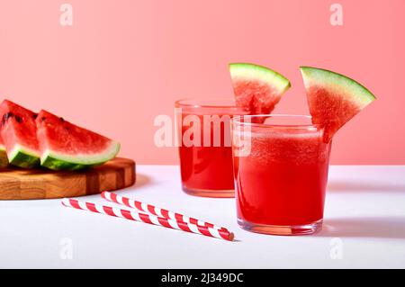 Primo piano succo di cocomero fresco o frullato in bicchieri con pezzi di cocomero su sfondo rosa. Foto Stock