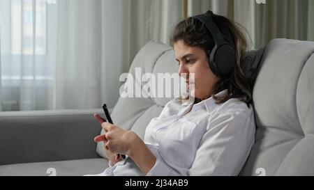 Donna con disabilità in cuffie ascolta musica in attesa telefono Foto Stock