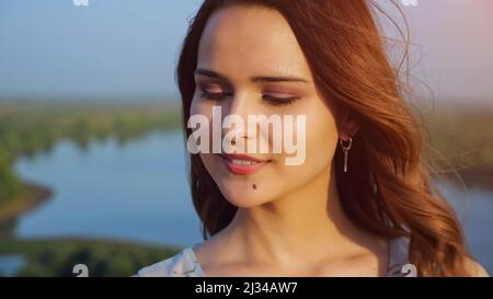 Bella donna con capelli volanti e trucco leggero sulla riva del fiume Foto Stock