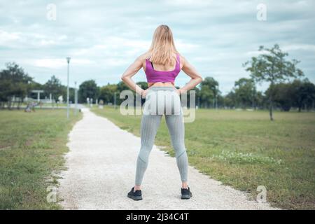 donna vestita e muscolosa in piedi nel parco Foto Stock