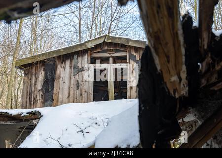 La vecchia cabina in legno nei boschi è un edificio abbandonato in condizioni pessime. Casa di legno in una zona rurale. Il tetto è rotto e abbassato Foto Stock