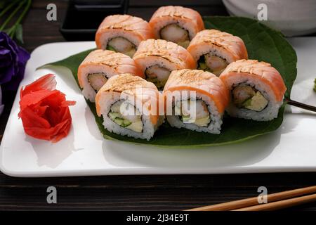 Kimono di sushi Maki con decor. Con salmone, gamberi, cetrioli, su un piatto, su sfondo di legno Foto Stock