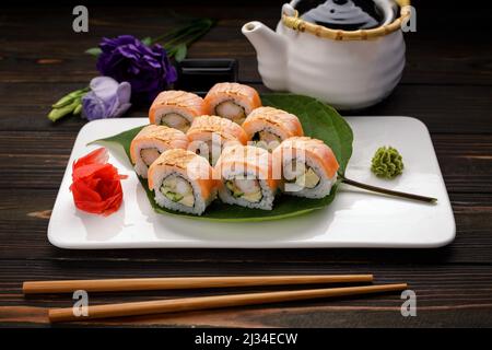 Kimono di sushi Maki con decor. Con salmone, gamberi, cetrioli, su un piatto, su sfondo di legno Foto Stock