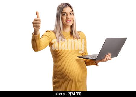 Donna incinta che tiene un computer portatile e mostra i pollici isolati su sfondo bianco Foto Stock