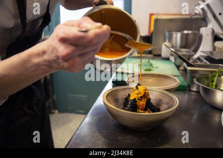 Un primo colpo della mano dello chef che decora un piatto con un po' di salsa. Foto Stock