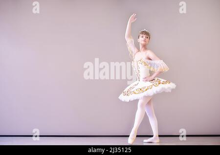 Giovane ballerina classica in studio è in piedi su tiptoe.Young bella ballerina caucasica pratica posizioni balletto in tutu gonna di Foto Stock