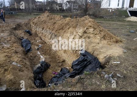 Bucha, Ucraina. 05th Apr 2022. NOTA REDATTORI - CONTENUTI GRAFICI gli ufficiali guardano una tomba di massa nella città di Buche, a nord-ovest della capitale Ucraina Kiev, lunedì. Aprile 4, 2022. L'Ucraina e le nazioni occidentali hanno accusato le truppe russe di crimini di guerra dopo la scoperta delle tombe di massa e dei civili che apparentemente sono stati giustiziati nei pressi di Kiev. Un funzionario di salvataggio ha detto che 57 persone sono state trovate in una trincea scavata frettolosamente dietro una chiesa. Foto di Vladyslav Musienko/UPI Credit: UPI/Alamy Live News Foto Stock