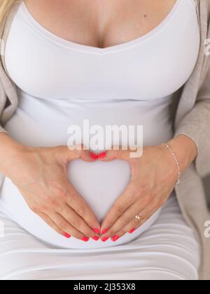 Inviare l'amore al suo piccolo. Colpo ad angolo alto di una donna incinta irriconoscibile seduta giù a casa. Foto Stock
