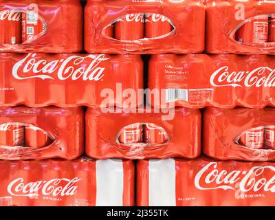 Coca Cola lattine imballate con plastica e immagazzinate in un supermercato. Foto Stock