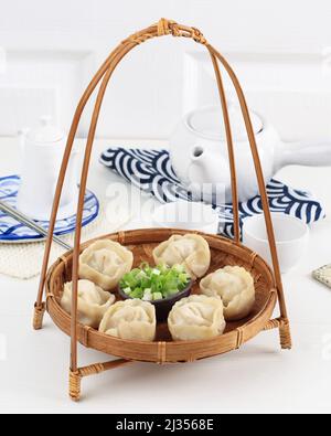 Mandu Dumpling al vapore, Dim Sum Street Food tradizionale coreano. Servito su un piatto di bambù con cipolla primaverile tritata e salsa di sale di soia Foto Stock