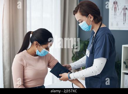 Im appena andando mettere questo intorno al vostro braccio. Shot di una giovane dottore femminile che controlla la pressione sanguigna di un paziente in un ufficio. Foto Stock