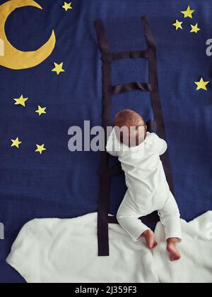 Il cacciatore di sogni. Concept shot di un bambino adorabile che sale su una scala contro un immaginario sfondo notturno. Foto Stock