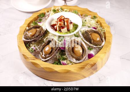 Abalone imperiale con foie gras in un piatto isolato su sfondo grigio vista laterale del cibo di Hong kong Foto Stock