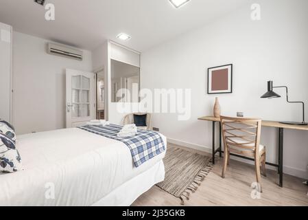 Camera da letto con letto matrimoniale, scrivania in legno con sedia coordinata e dettagli decorativi Foto Stock