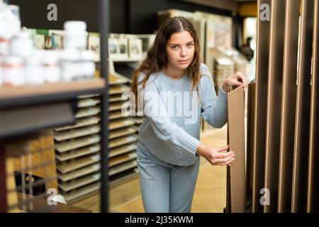 Cliente femmina che tiene campioni di pannelli di legno nel negozio di ferramenta Foto Stock