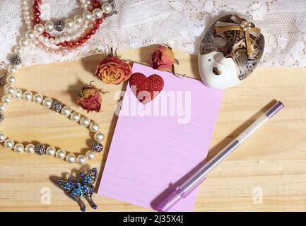 Perla Gioielleria e broccia di farfalla con pizzo e rose secche su sfondo di legno con carta bianca Foto Stock