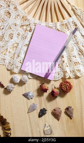 Notepaper su Vintage Lace Fan con rose secche e frecce native americane su sfondo di legno Foto Stock